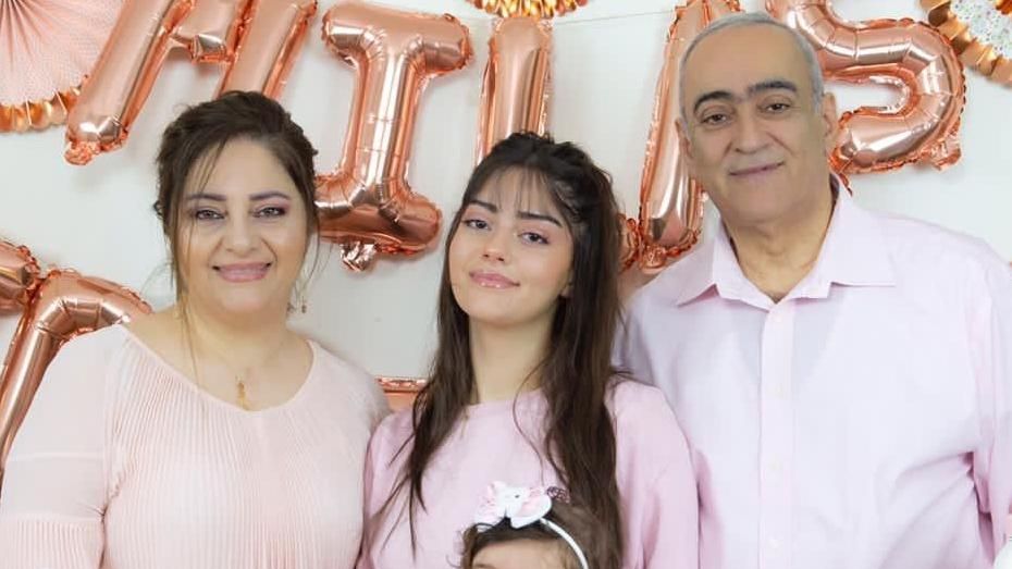 Carla (middle) standing with her mother (left) and father (right), dressed all in pink with rose gold lettered balloons behind them