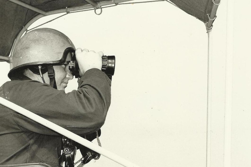 A man on a boat looking through binoculars.